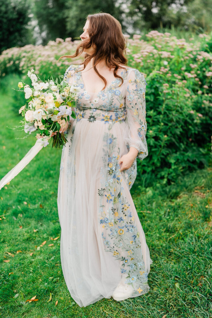 woman in a floral wedding dress in nature holding a bridal bouquet