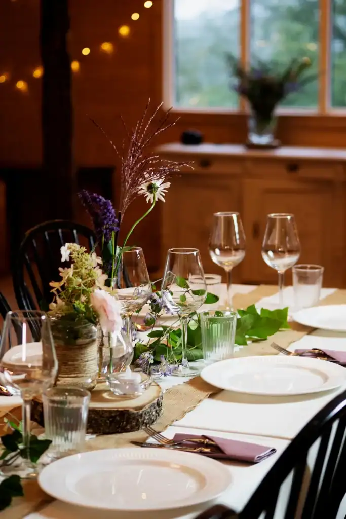 long table with flowers and fine cutlery for a party with twinkle lights in the background