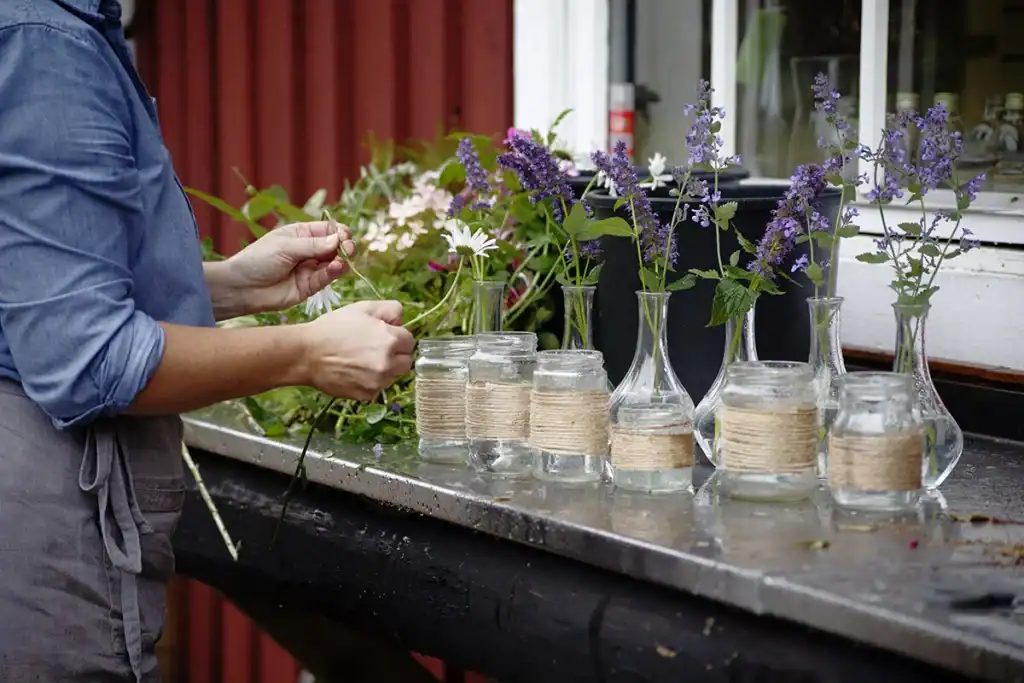 a womans hands filling up little vases with flowers