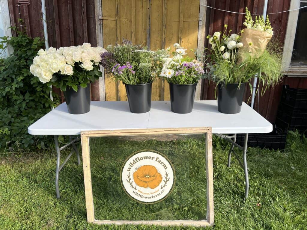 4 buckets of flowers on a table with a sign in front of it