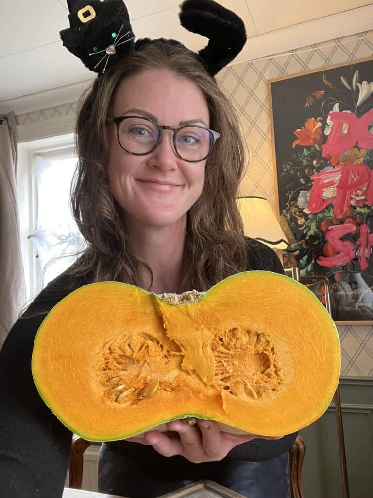 a woman with a cat headband holding a half cut open pumpkin